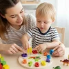 Toddler learning to tell time with dinosaur wooden clock in Pakistan