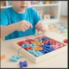A young child practicing fine motor skills by threading a blue lace through wooden alphabet beads, a STEM toy for preschoolers.